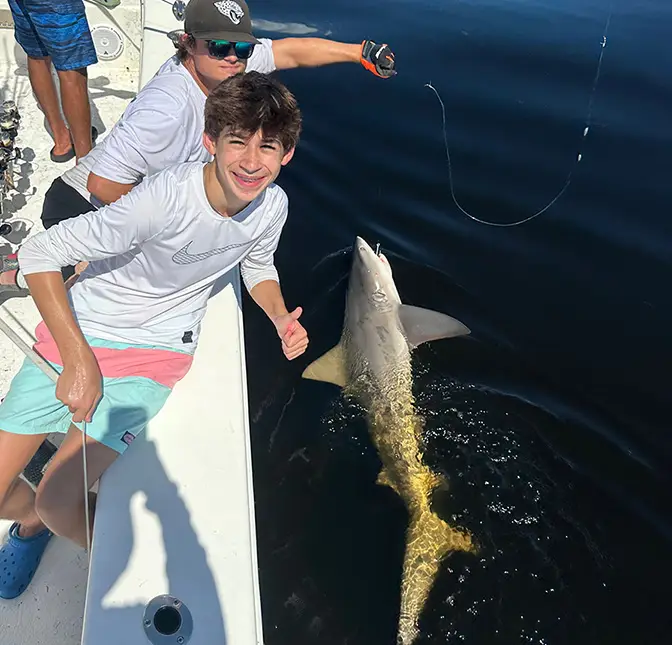 Two teenage boys with a shark pulled up alongside their boat in St. Pete