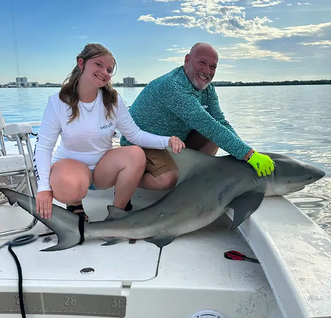 Father and daughter posing with a large shark before release in Clearwater